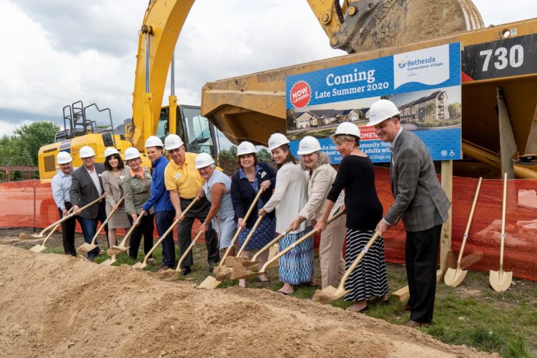 A construction site with several people holding shovels, ready to break ground.